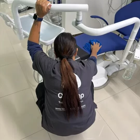 Limpieza de consultorios: Fotografía de una mujer limpiando con un paño color azul una silla de consultorio.